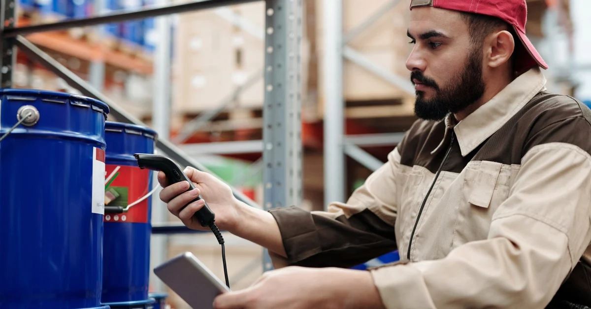 Warehouse worker scanning food packaging for PFAS compliance and documentation.