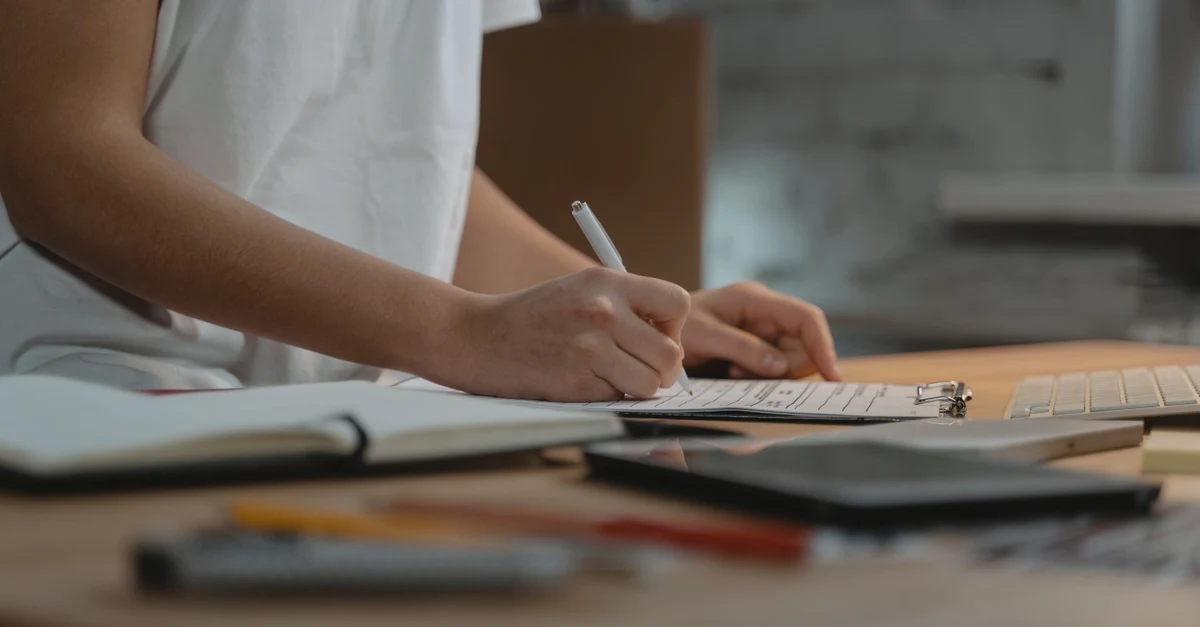 Hand writing PFAS compliance documentation and test reports for foodservice packaging distributors