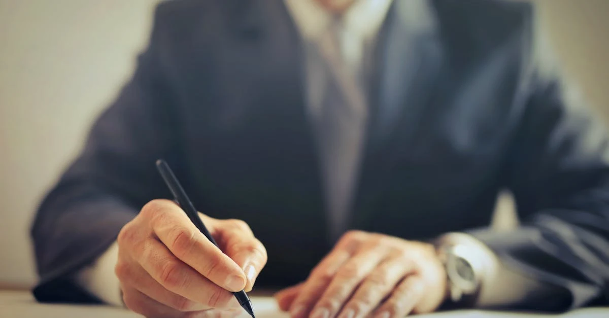 Businessman in suit signing document with pen, demonstrating closing technique for selling compostable packaging deal.