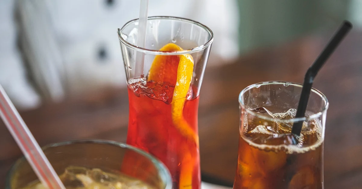 Red cola drink with ice and straw in glass, sustainability FAQ for distributors showing beverage packaging.