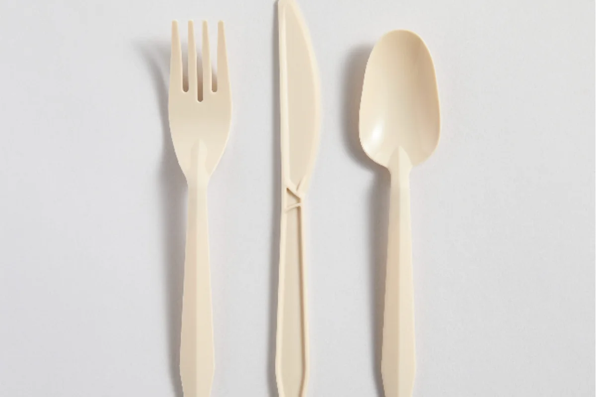 Three beige plastic utensils—fork, knife, and spoon—arranged vertically on a plain white background, conveying simplicity and functionality.