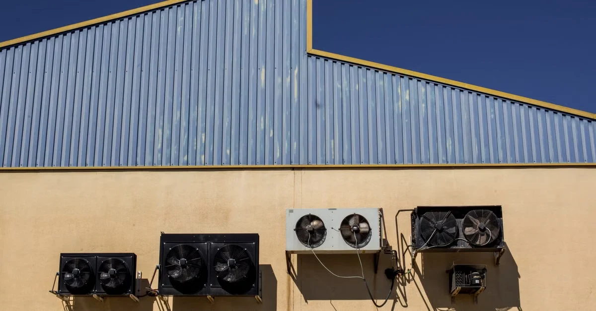 Industrial HVAC units mounted on beige building wall demonstrating temperature control for compostable product shelf life.
