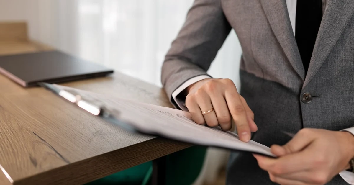 Businessperson reviewing sourcing documentation at desk with laptop for compostable products comparison analysis.