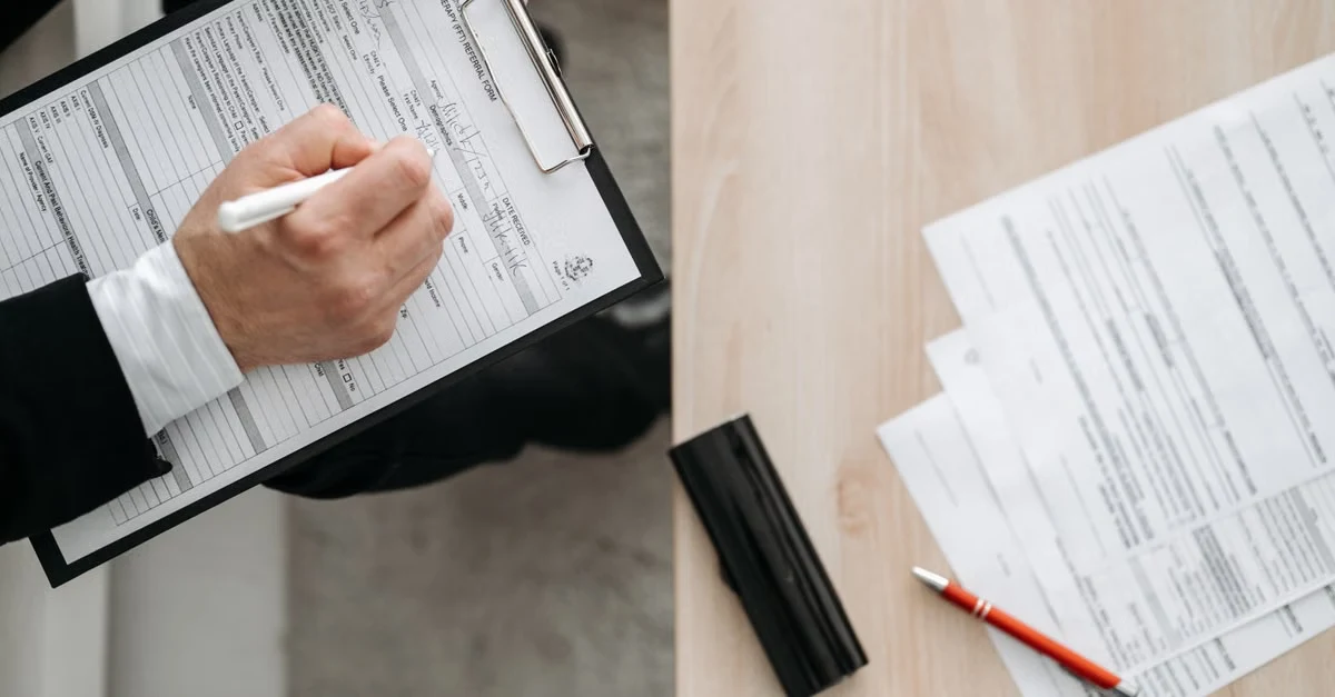  Person reviewing compostable packaging suppliers checklist with pen on clipboard.