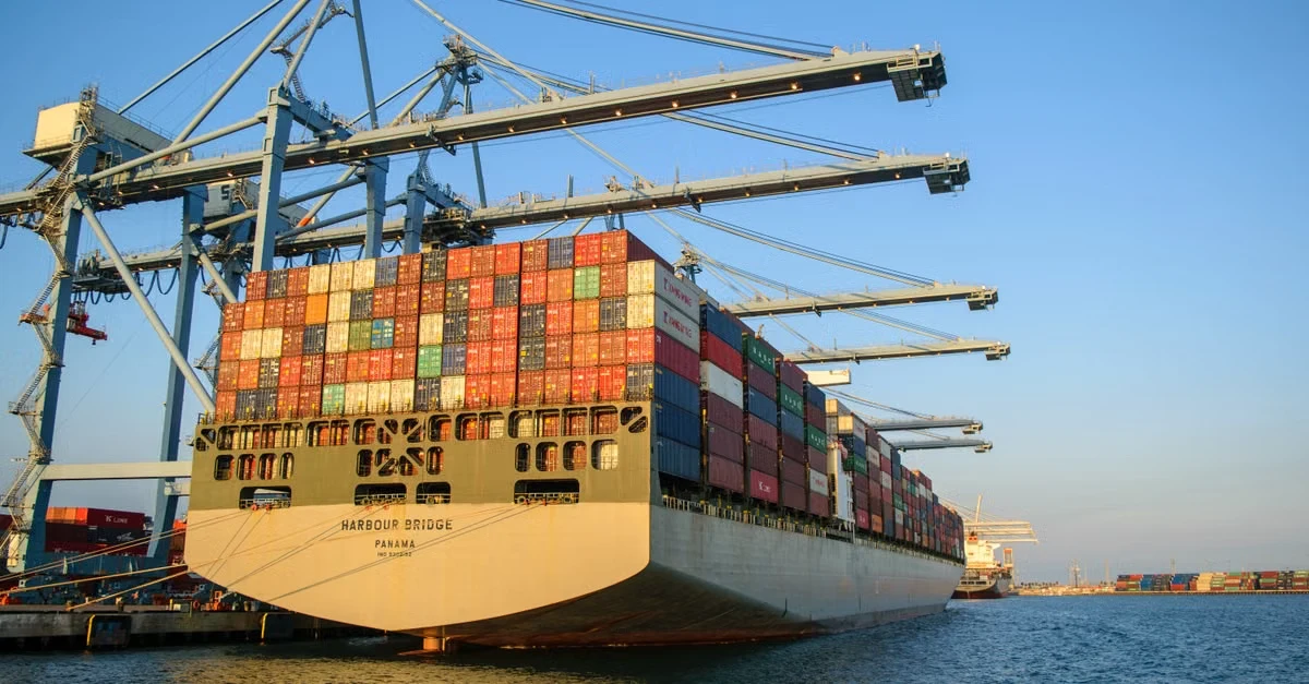 Large cargo ship loaded with colorful shipping containers at port, illustrating compostable products sourcing supply chain.