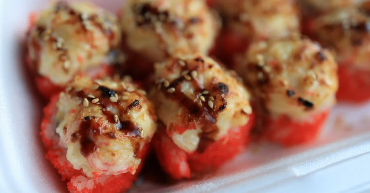 Crab-stuffed red bell pepper halves topped with breadcrumb crust on white plastic container.