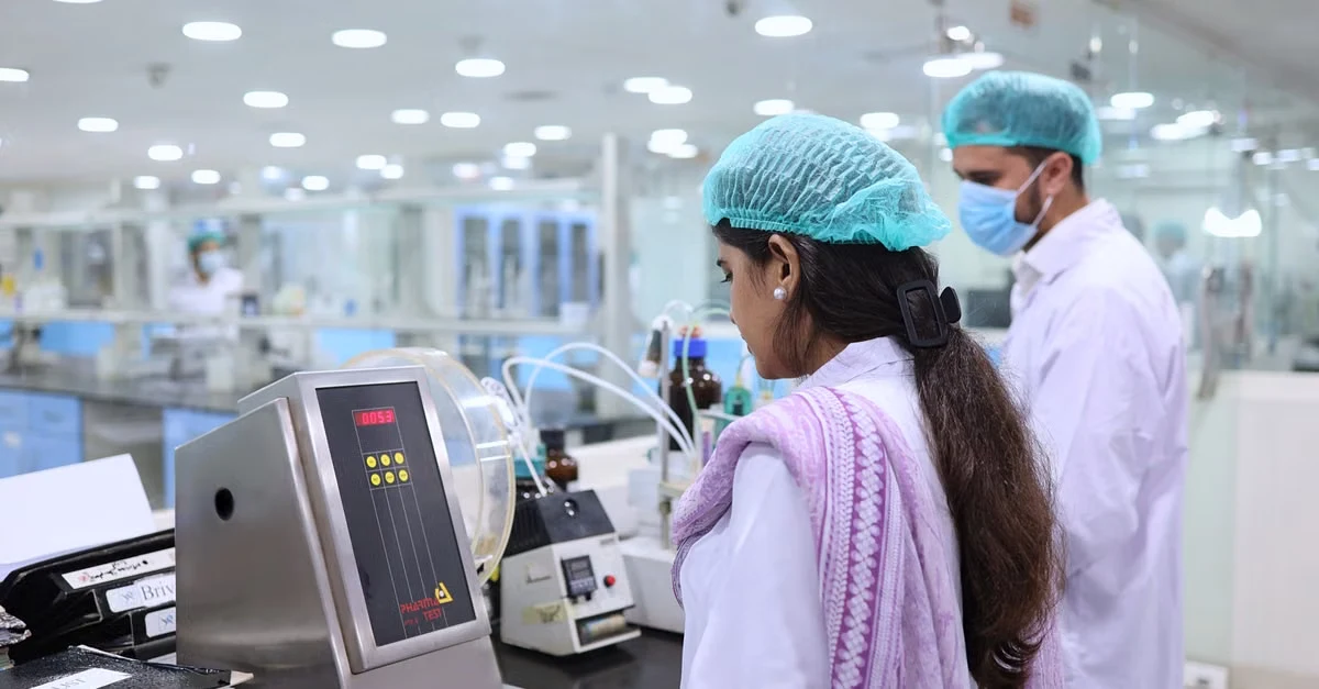 Laboratory technician operating medical analyzer equipment in clinical facility with modern diagnostic instruments.