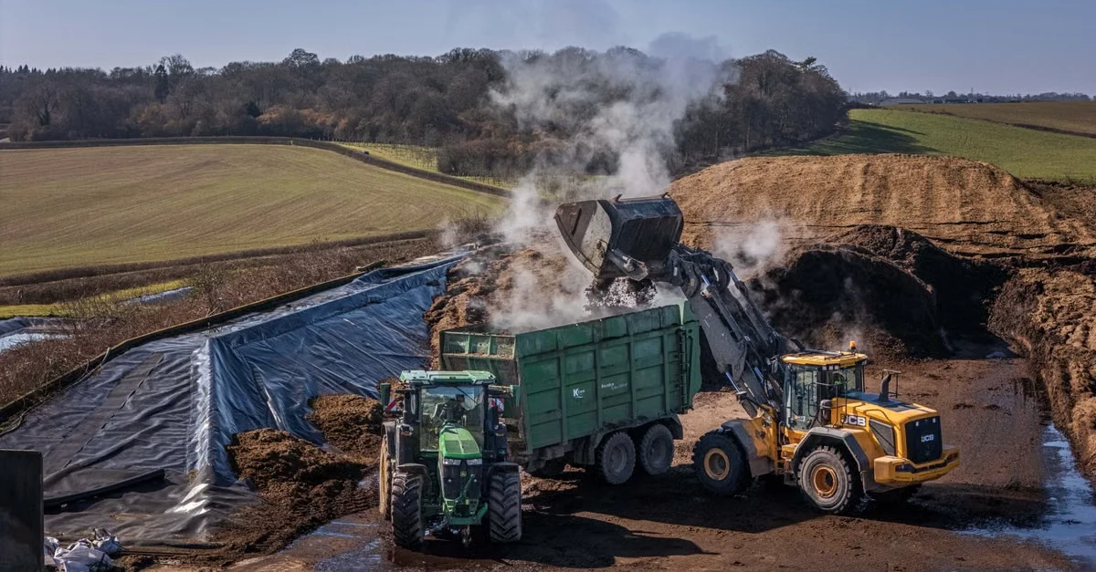 Industrial composting facility with heavy machinery processing organic waste on large farm scale operation.