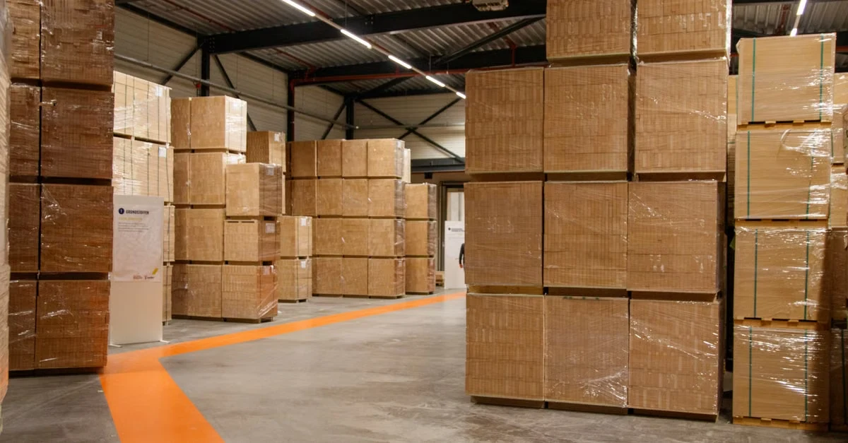 Cardboard boxes stacked in warehouse with orange floor marking showing compostable storage requirements.