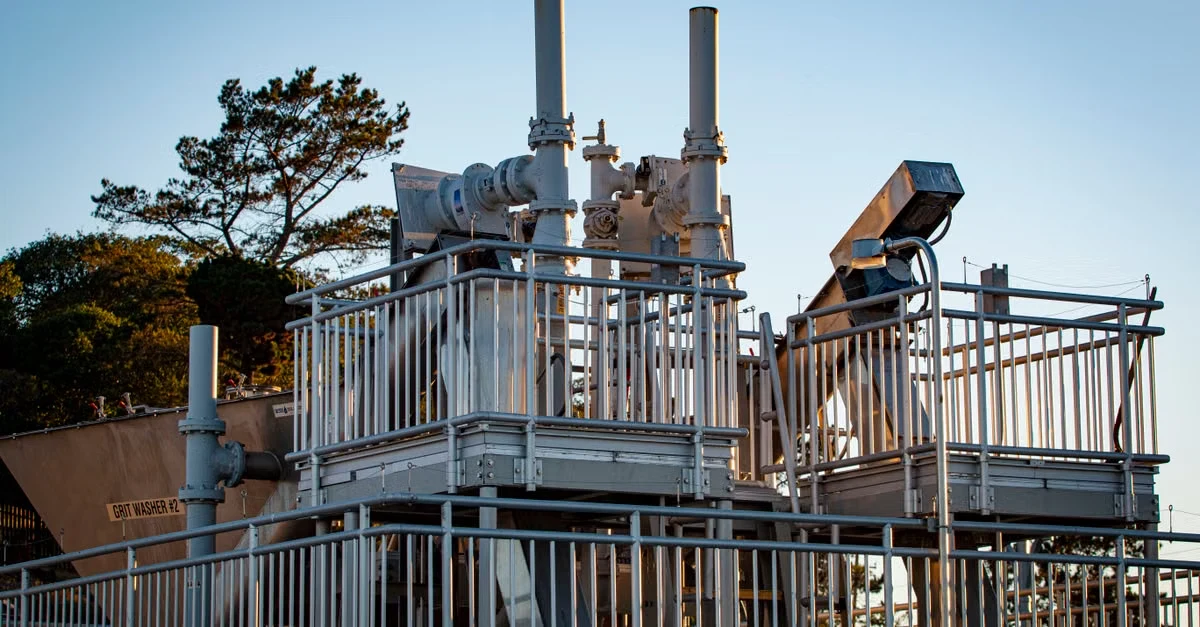 Industrial composting facility with dual digesters and metal infrastructure against clear sky.