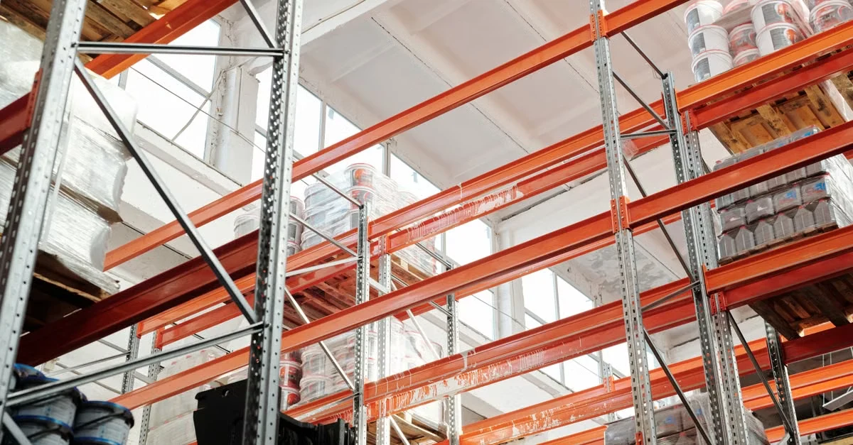 Industrial warehouse shelving with orange beams storing compostable storage requirements in organized bins.