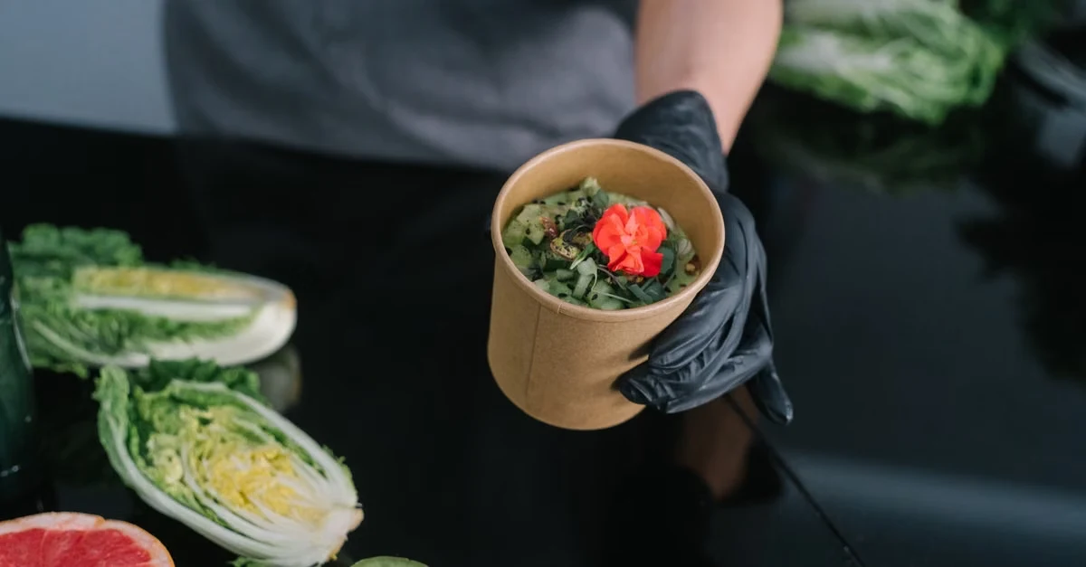 Chef holding compostable cup of greens with fresh vegetables, demonstrating sustainable composting infrastructure for.