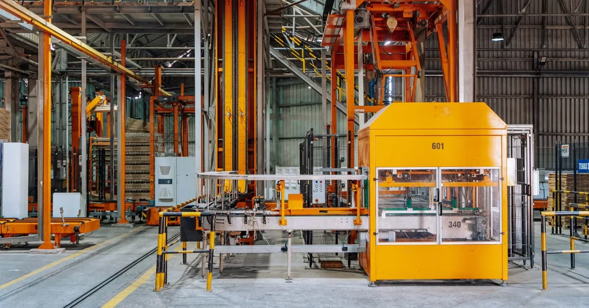 Industrial composting infrastructure facility with large yellow processing equipment and machinery on factory floor.