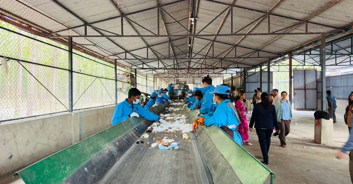 Workers sorting compostable straws and materials at municipal composting facility conveyor belt system.